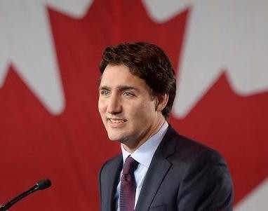 Justin Trudeau w swobodnej interakcji z ludźmi, uśmiechnięty i gestykulujący, ukazujący swoją charyzmę.