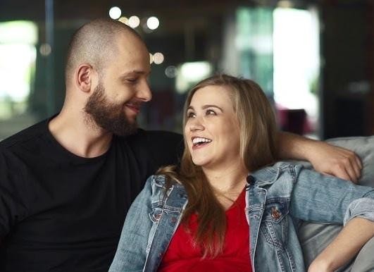 Maciej Pela w czułej interakcji z dwiema małymi córkami, symbolizującej więź rodzinną.