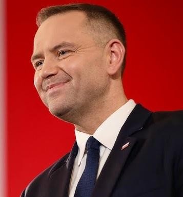 Karol Nawrocki podczas wystąpienia publicznego, z tłem symbolizującym polską historię i dziedzictwo.