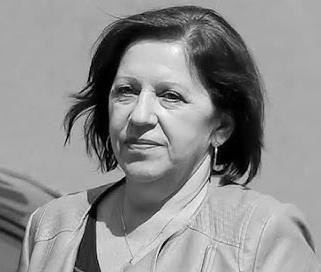 Protokół przesłuchania świadka leżący na stole, w tle zamazane sylwetki osób, symbolizujący proces sądowy.
